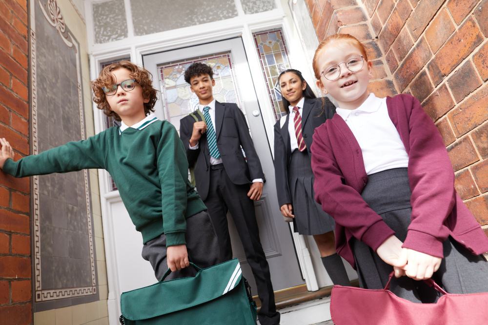 A group of children on the doorstep of a house wearing school uniform by David Luke