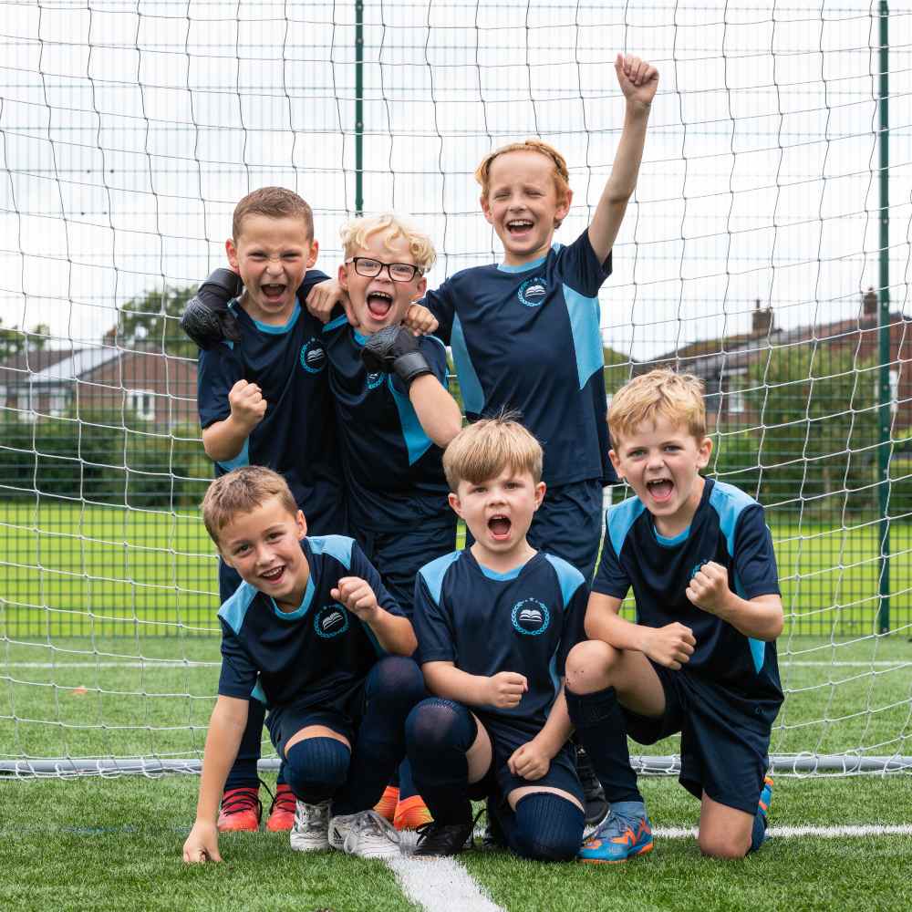 A group of children outside in front of a football net wearing sportswear by JUCO