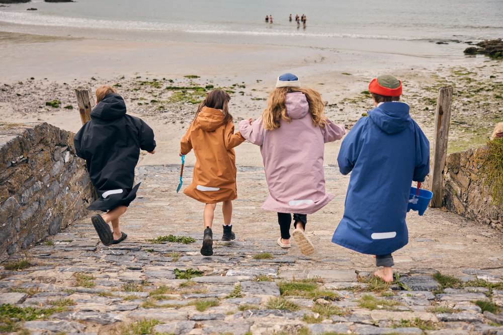 Children running down to a beach wearing Evo Pro Change Robes by Red Equipment 