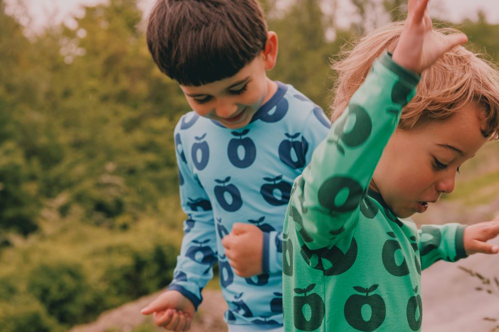 Two boys playing outside wearing blue and green apple print tops