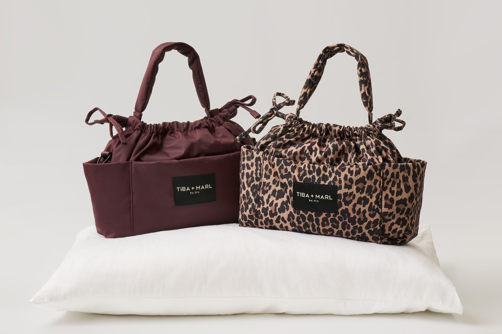 Burgundy and leopard print baby changing bags by Tiba + Marl displayed on a cushion