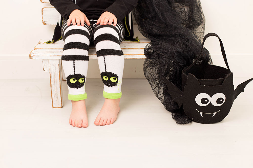 A young girl sat on a bench wearing leggings with a spider print