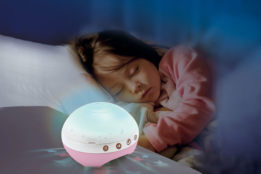 A young girl in bed asleep next to the 3-in-1 projector musical mobile