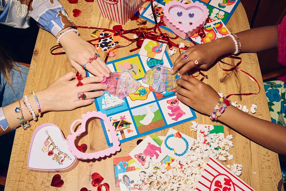 Two young girls wearing rings and bracelets playing with toys on a table