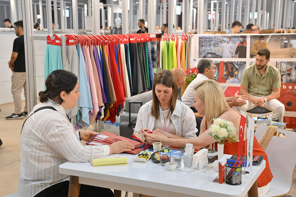 Visitors sat down at a table on a exhibition stand looking at fabric samples