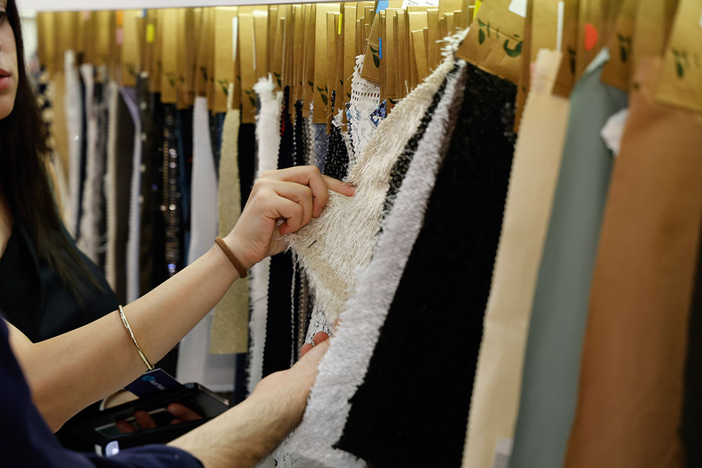 A vistor looking through fabric samples hanging from a rail