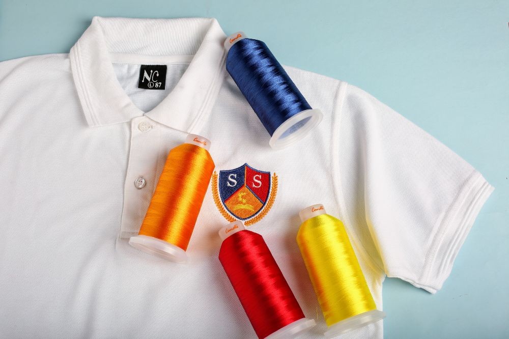 An embroidered school polo with spools of thread displayed on it