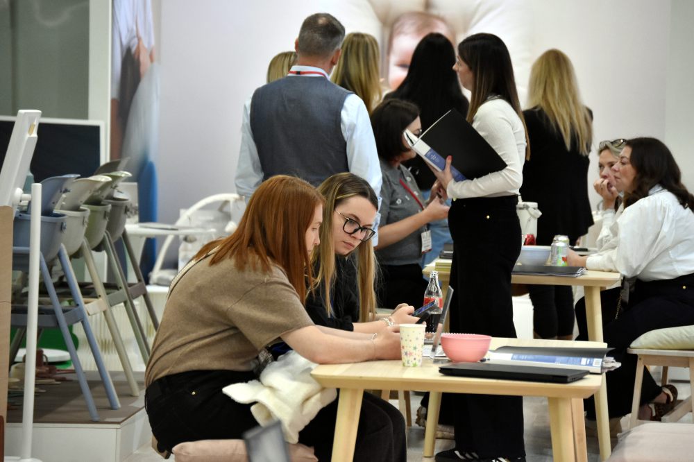 People sat at a table working and people stood on a stand at Harrogate International Nursery Fair 2025 