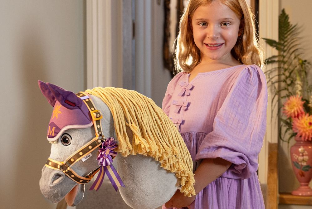 A young girl holding a Hobby Horse from the new Disney collection by LeMieux