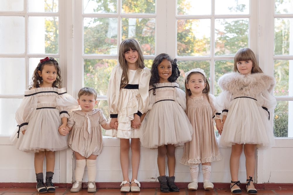 A group of children stood in front of a large window wearing occasionwear by Petite Maison Kids