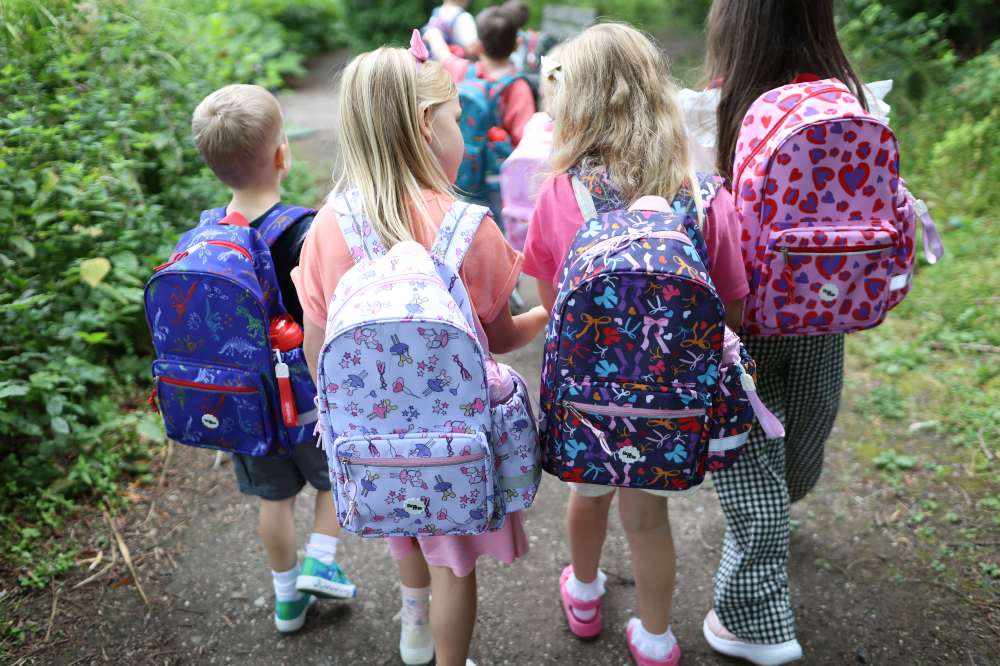 Children walking outside wearing backpacks by Roamie 
