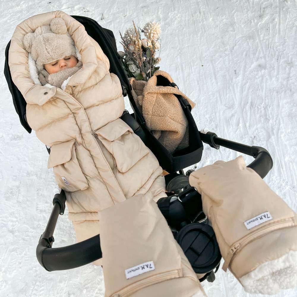 A baby wrapped up in a pram outside in the snow