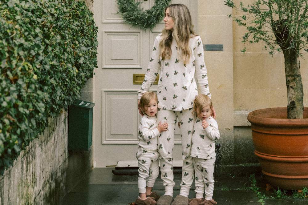 A woman stood outside a house with two children all wearing holly print pyjamas by Organic Zoo