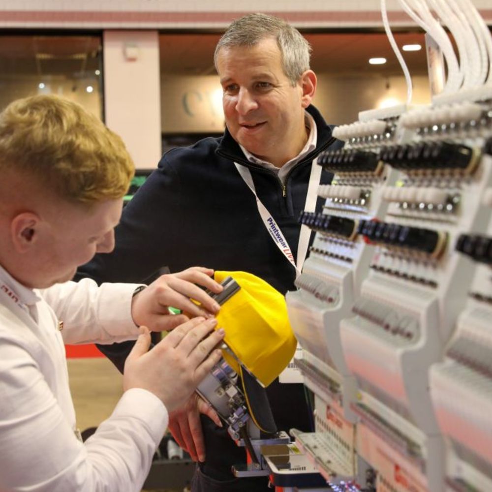 A man demonstrating an embroidery machine at Printwear & Promotion LIVE! 