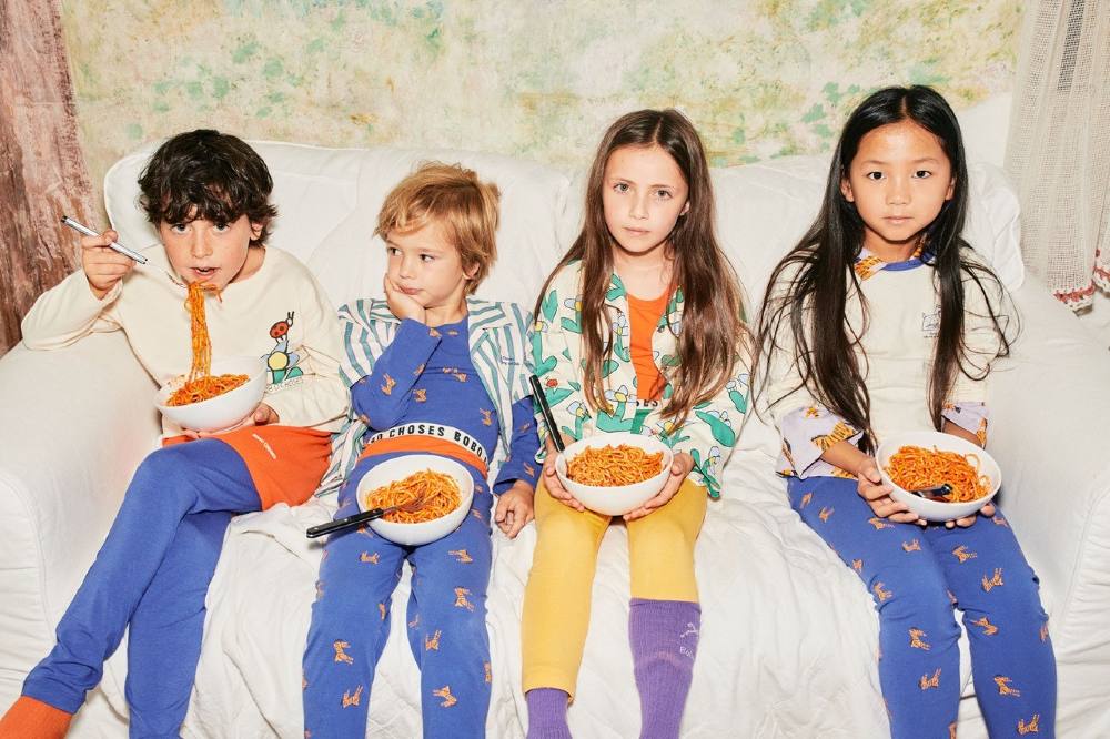 Four children holding bowls of spaghetti wearing outfits by Bobo Choses