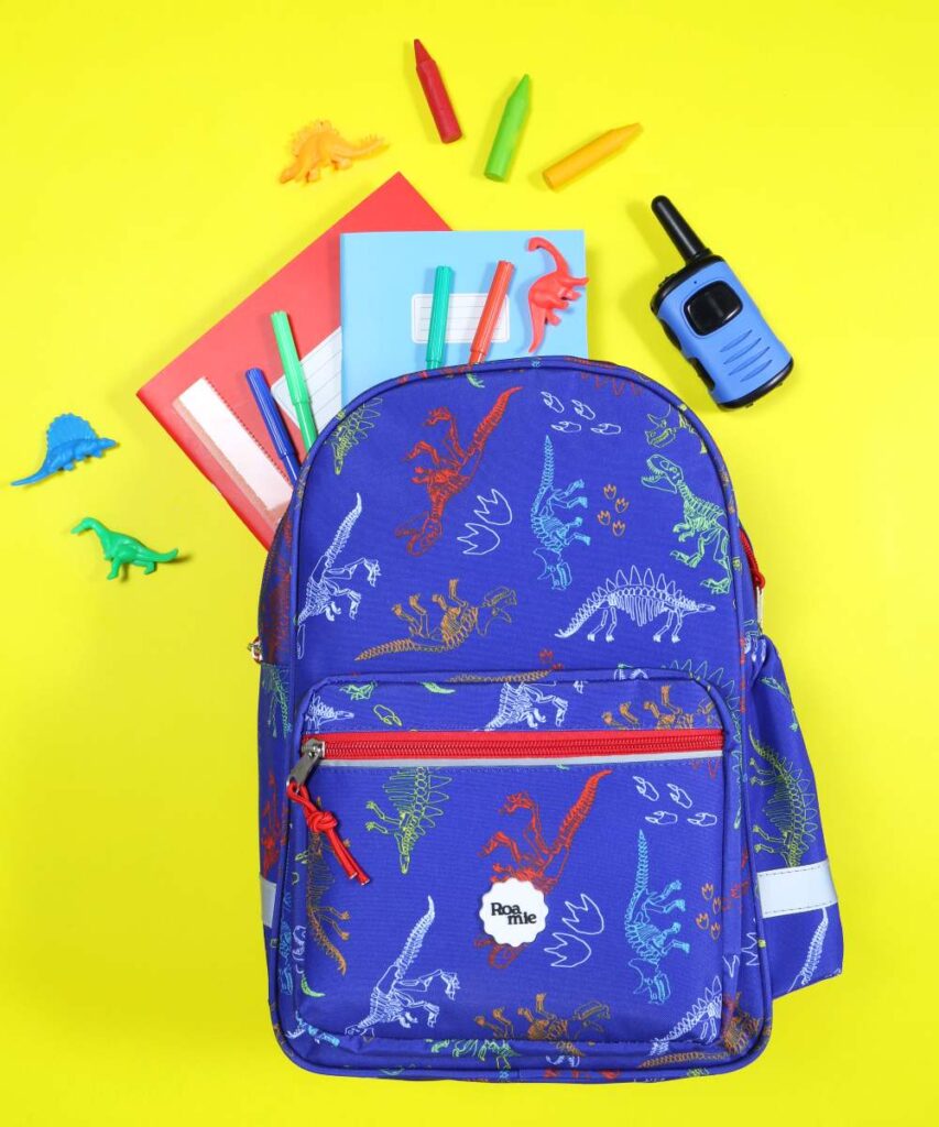 A dinosaur backpack, water bottle, pencil case and lunch bag by Roamie by William Turner displayed on a yellow background 