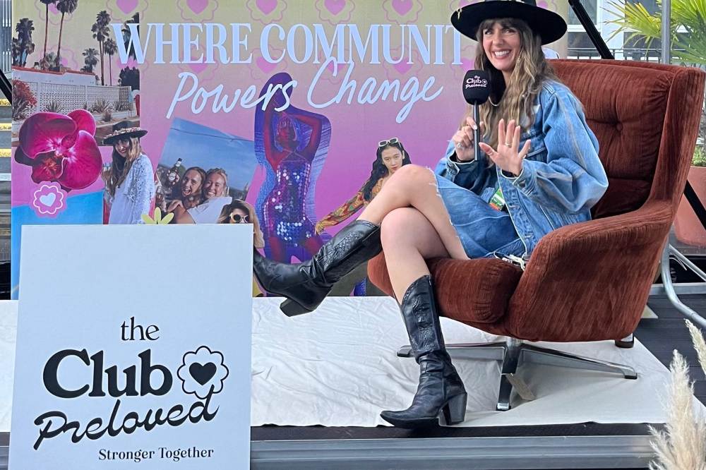 Lauren Cooley, founder of The Club Preloved, sat on a sofa with a microphone at an event