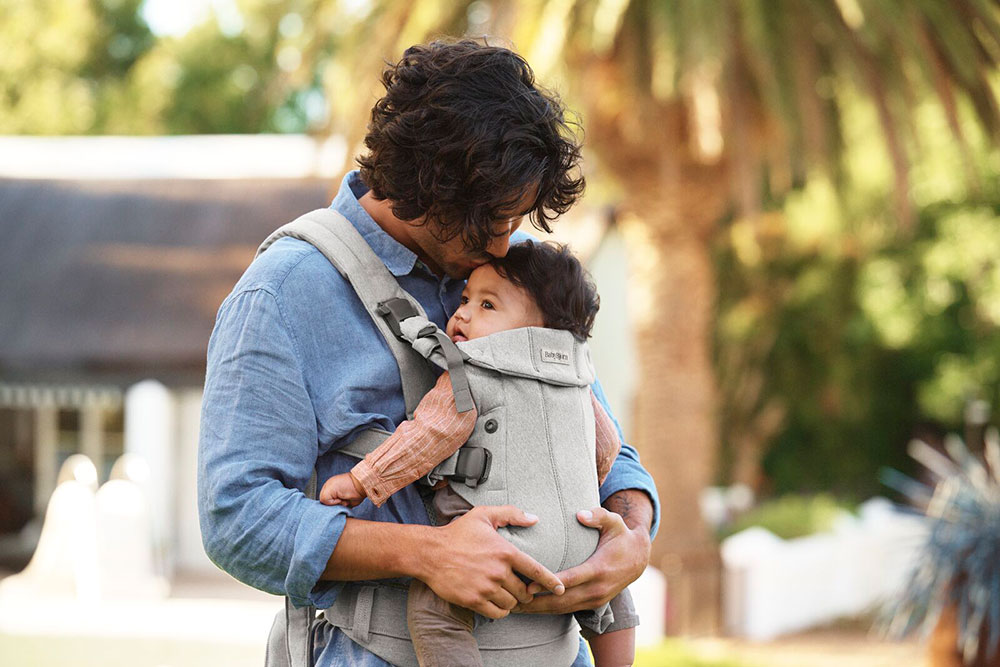 A man carrying a baby in a baby carrier