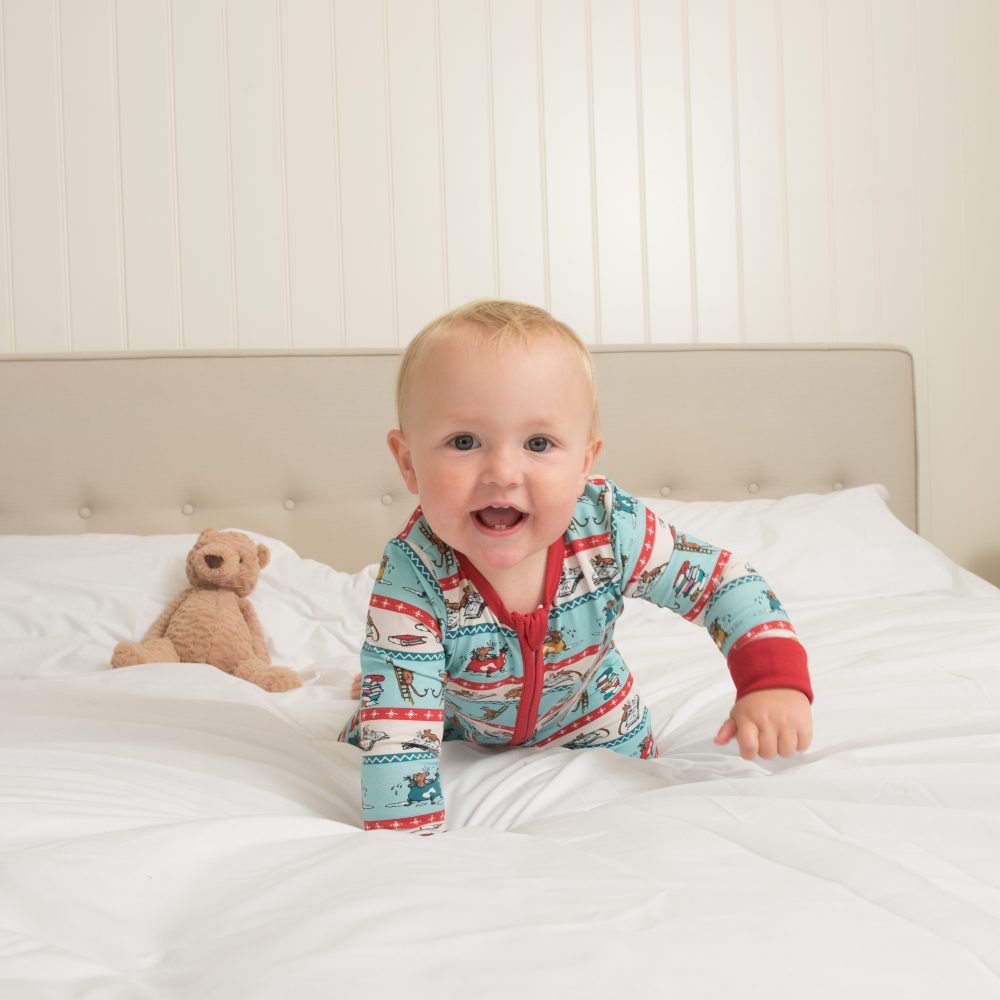A baby on a bed wearing a Roald Dahl print babygo 