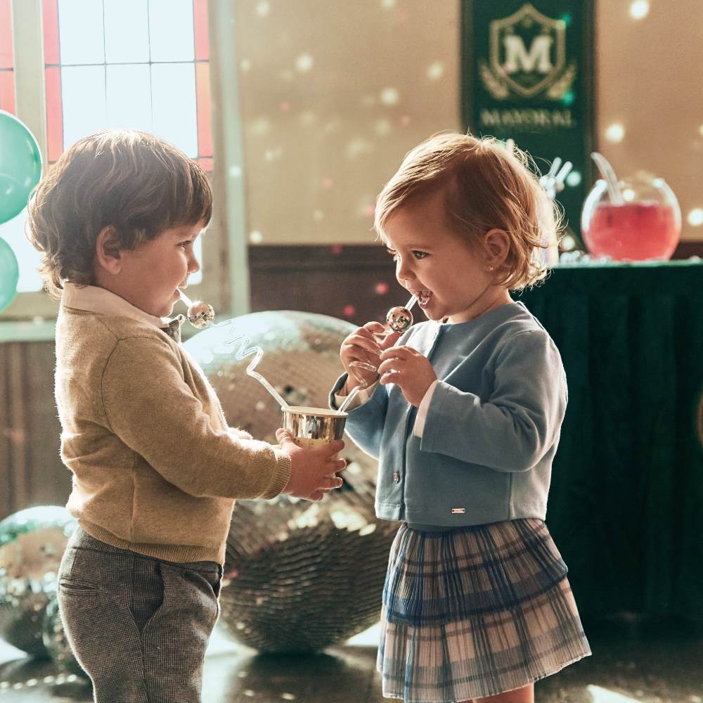 Two young children at a party with a table and disco balls in the background 