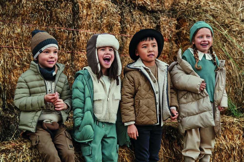 A group of children in winter stood outside in front of hay bales
