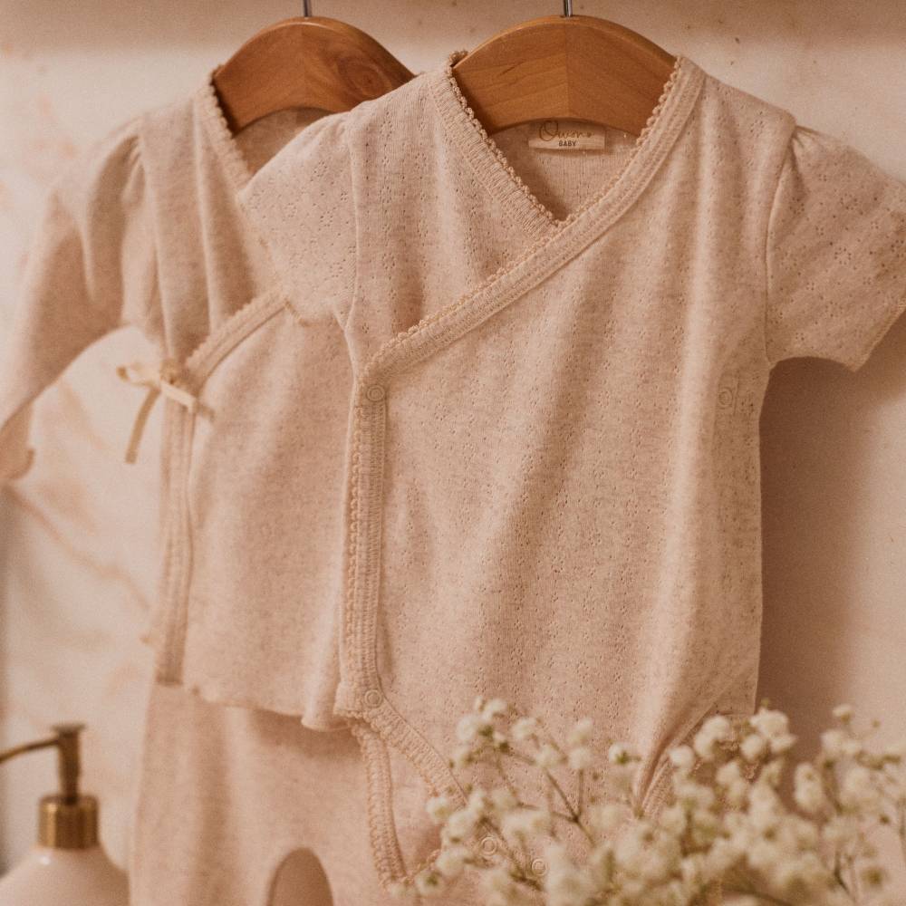 Two baby sleepsuits by Owono Baby hung on a wall 