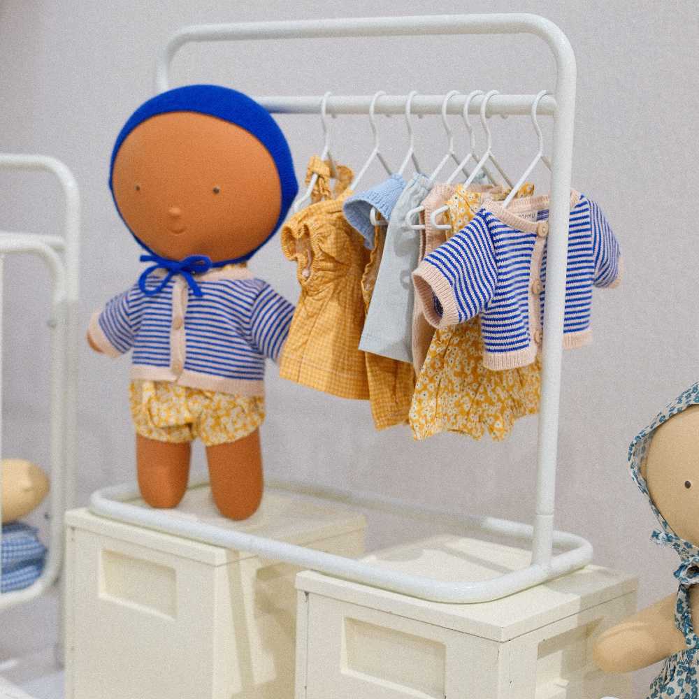 A doll and a rail of doll's clothes on display at Playtime Paris 