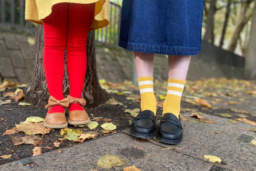 Two children's feet and legs shown stood outside on a pavement wearing shoes by Young Soles 