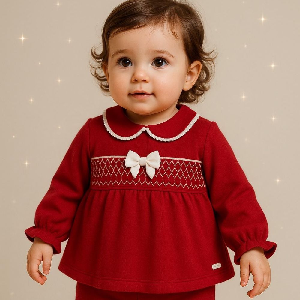 A toddler in a red outfit with a white bow by AMORE