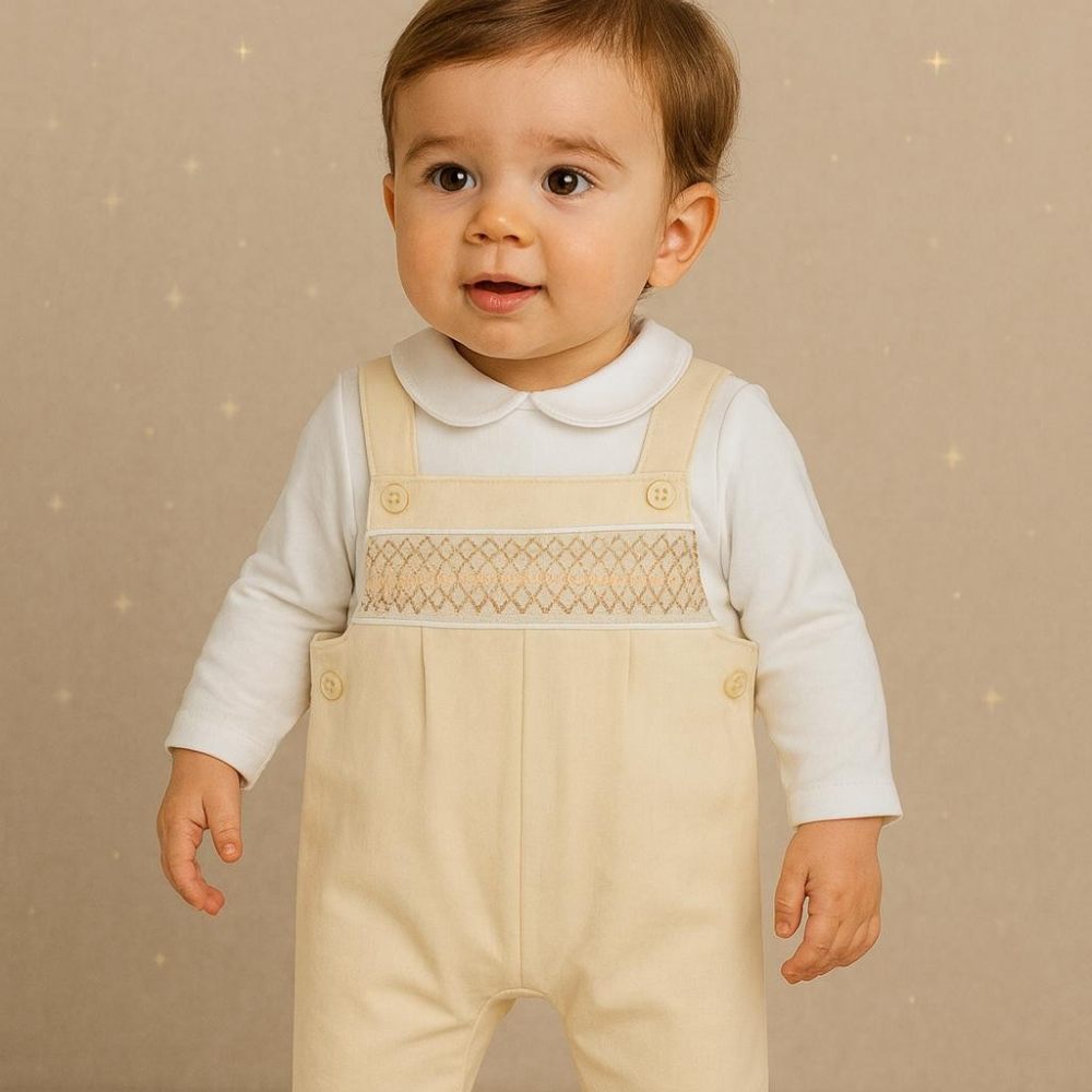 A toddler in a white top and beige dungarees by AMORE 