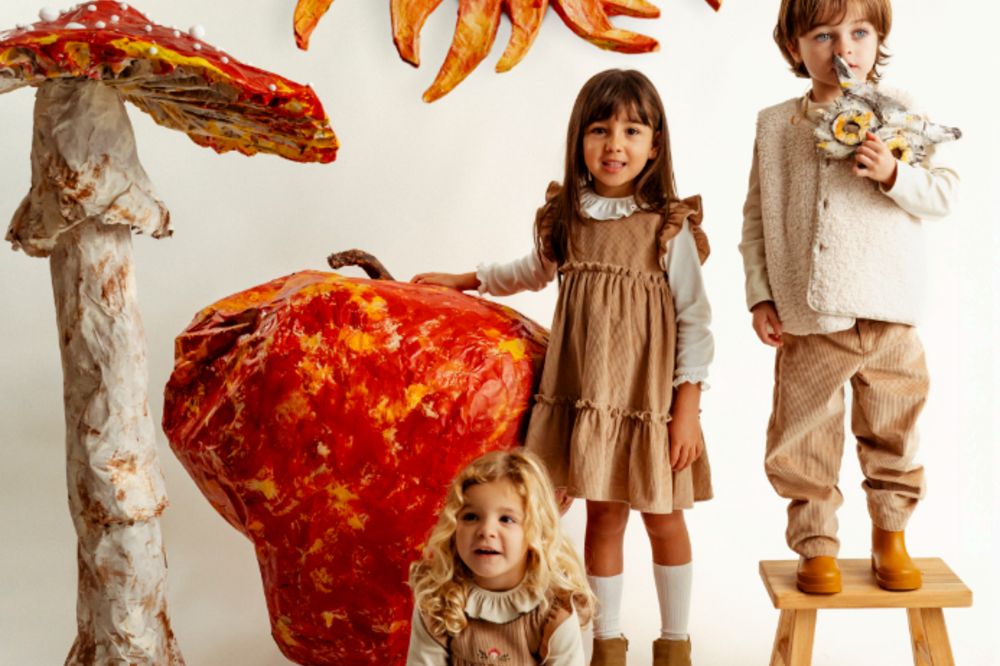 Three children stood among a large mushroom and apple display