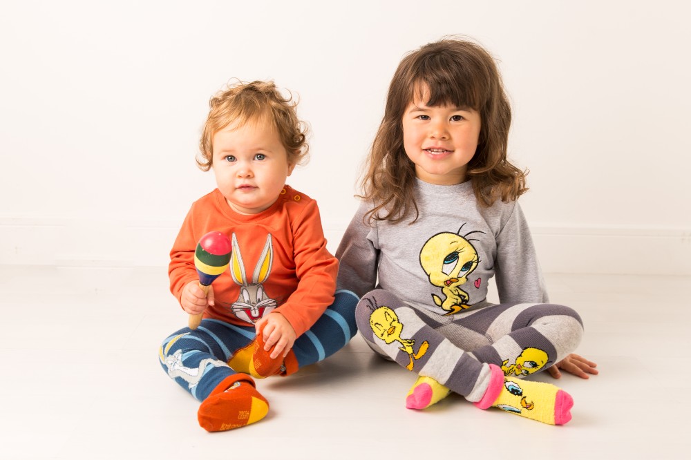 Two young children sat on the floor wearing outfits from Blade & Rose's new Warner Bros. character collections