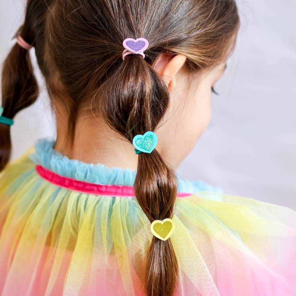 The back of a girl's head showing her hair in heart hair bobbles and a colourful cape 
