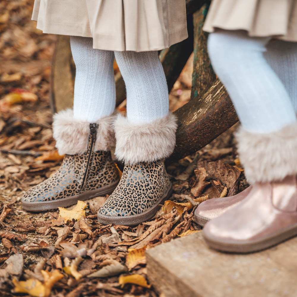 Two girls legs shown stood outside in leaves wearing white tights and fur lined boots by Froddo 