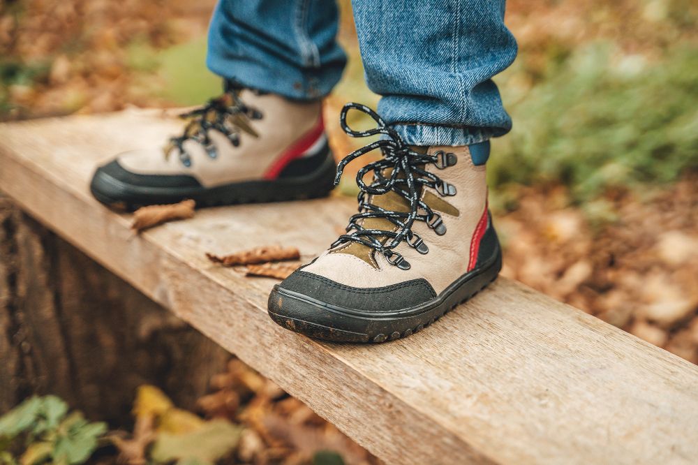 A child's feet stood on a bench in hiking boots by Froddo