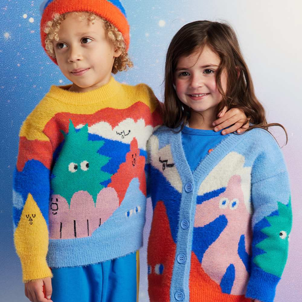 Two children stood together in brightly coloured outfits by Halcyon Nights 