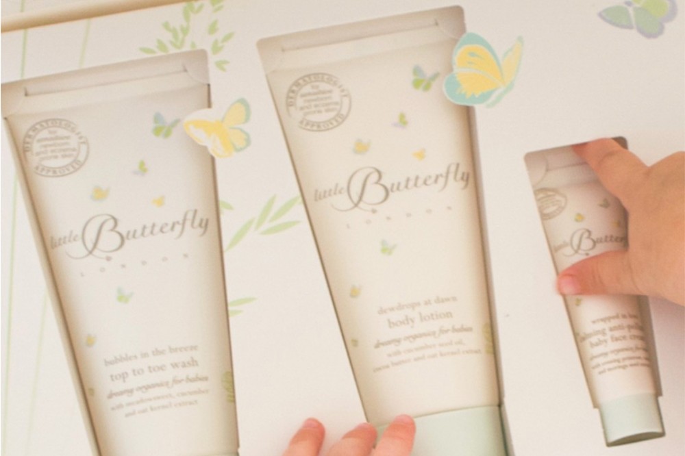 A child's hand shown opening a box of Little Butterfly London toiletries