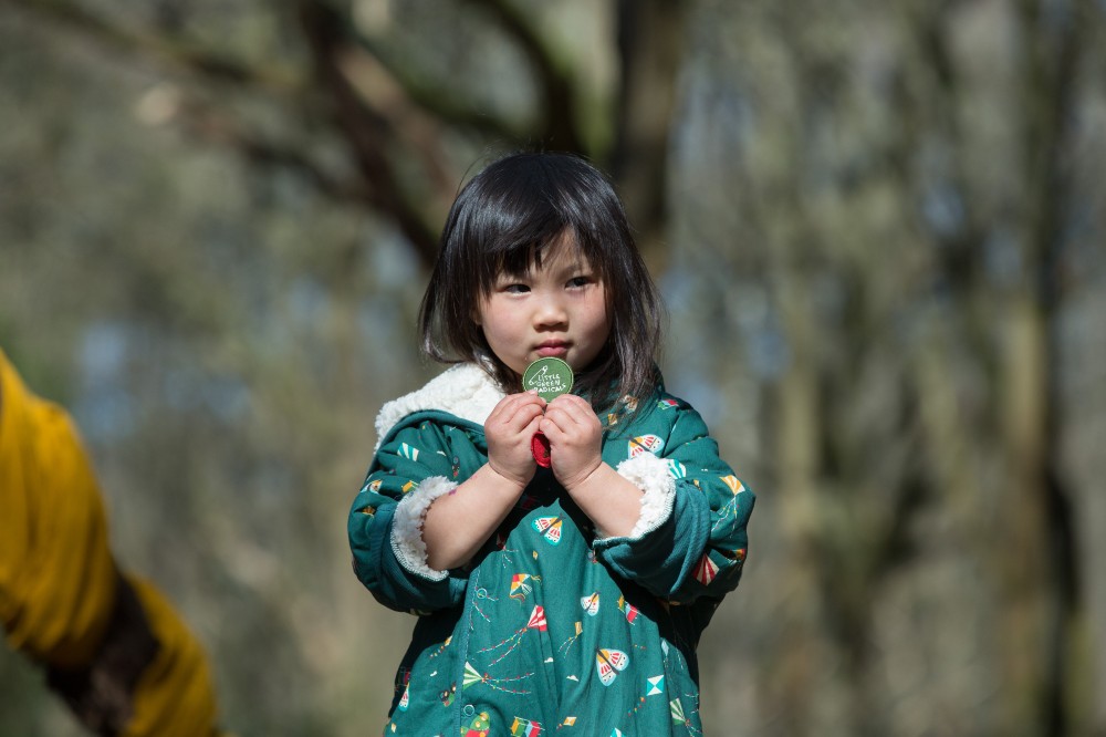 A girl stood in a wood wearing a green jacket by Little Green Radicals