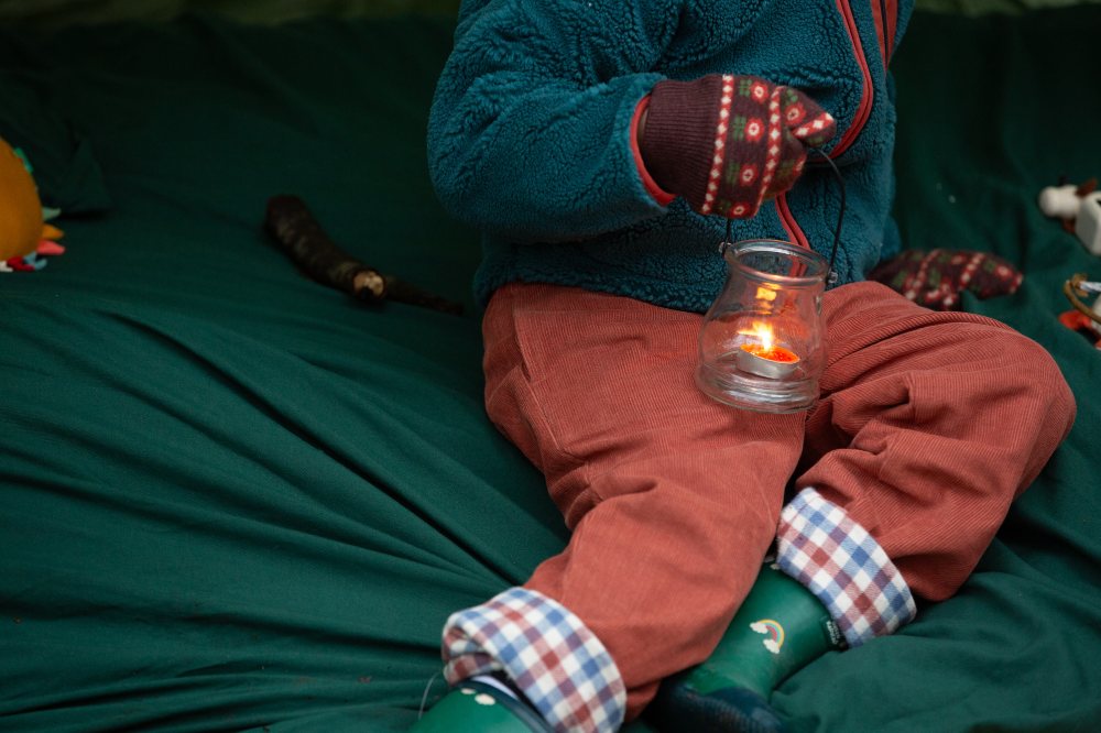 A child shown wearing winter clothes and holding a lantern