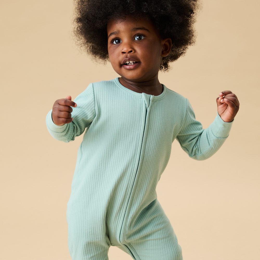 A young girl stood in a mint coloured MORI sleepsuit 