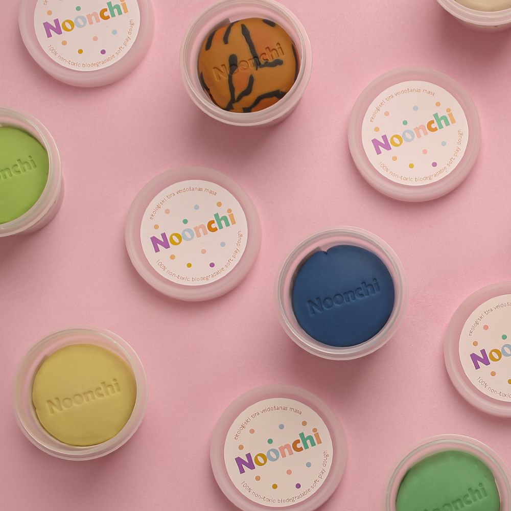 Pots of children's play dough displayed on a pink background 