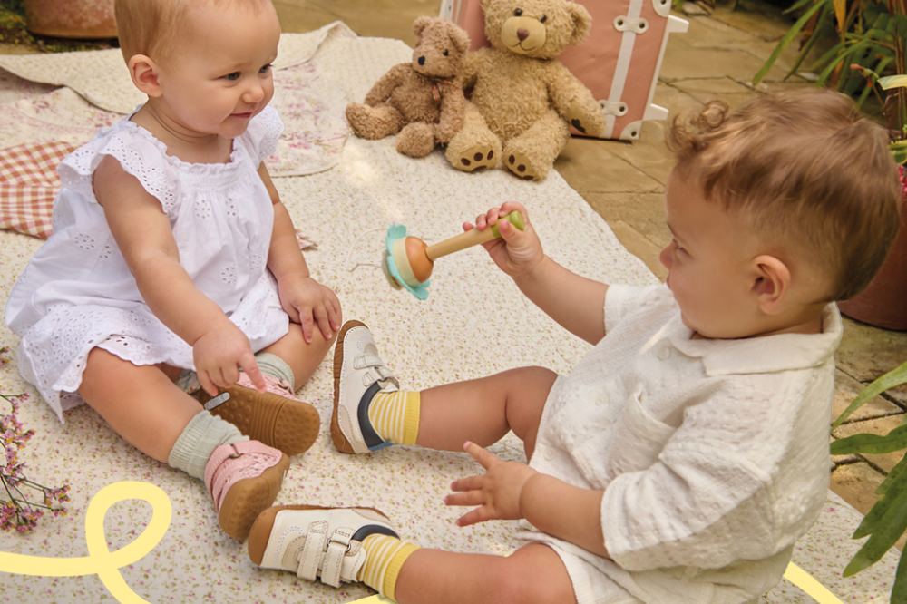 Two babies playing on the floor wearing shoes by Start-Rite
