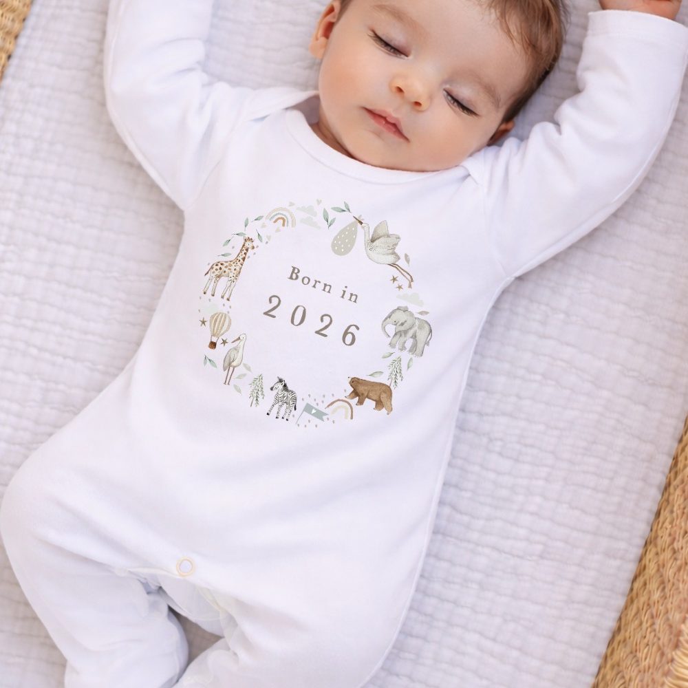 A sleeping baby wearing a babygro with animals and 'Born in 2026' on the front 