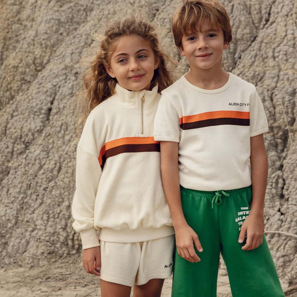 Two children in Mini Rodini outfits stood outside in front of a rock face 