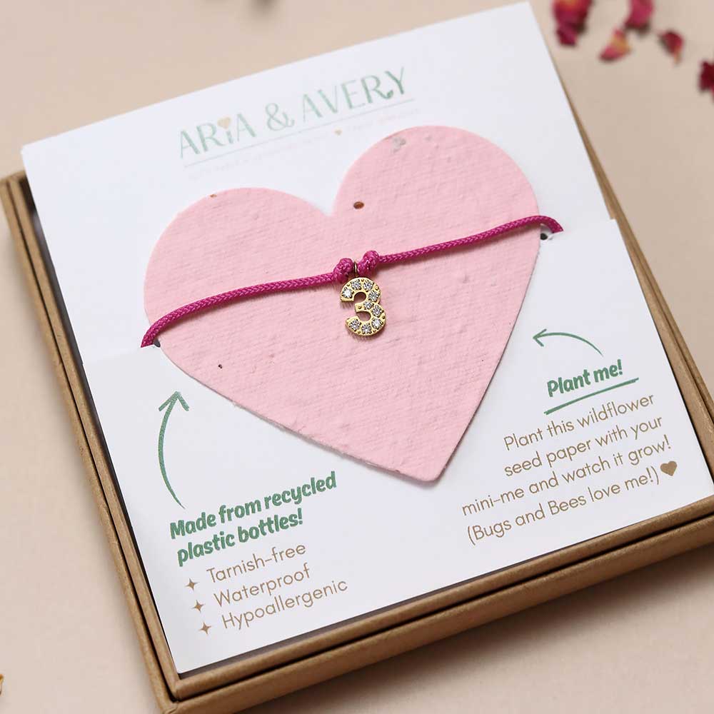 A child's bracelet with a number 3 charm displayed in a gift box 