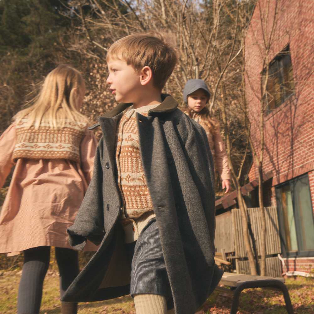 Children outside in a garden wearing winter outfits 
