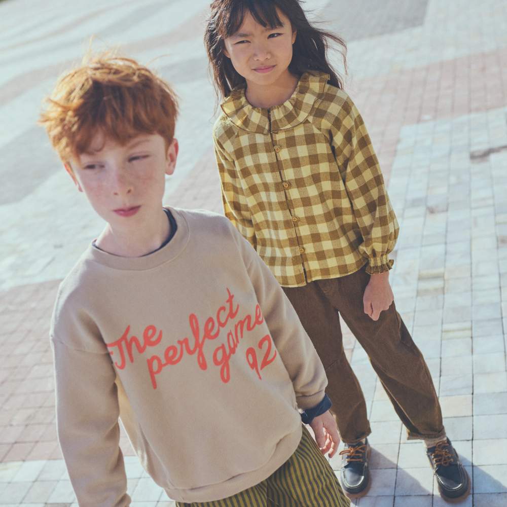 Two children stood outside on a pavement 
