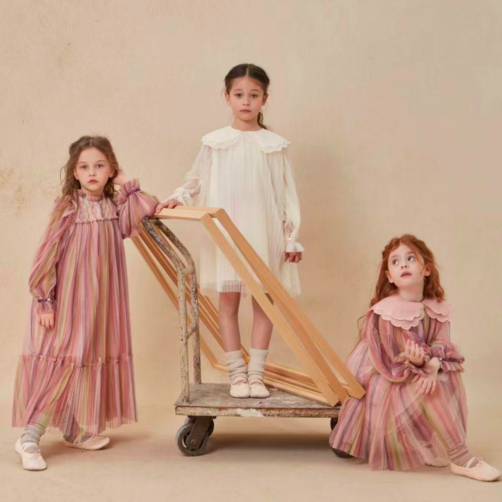 Three girls in dresses stood by a trolley 
