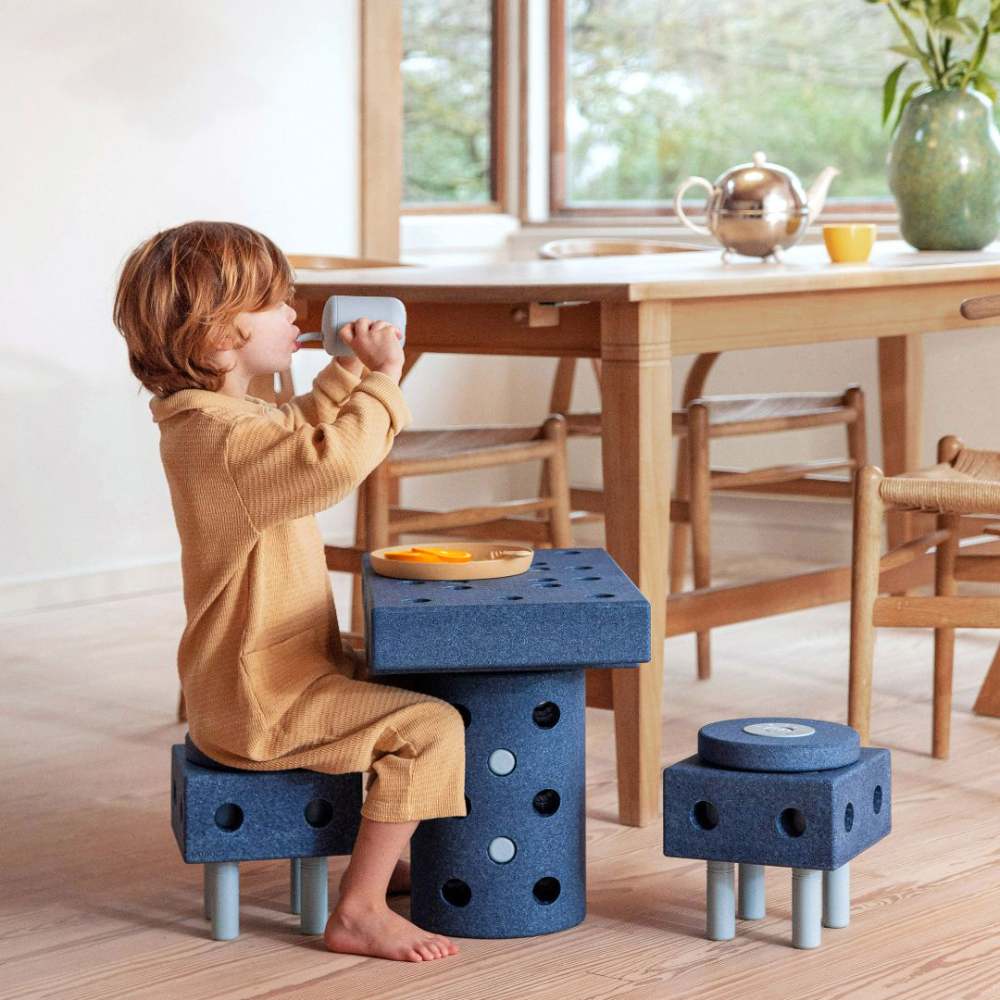 A boy sat at a table made of MODU blocks 