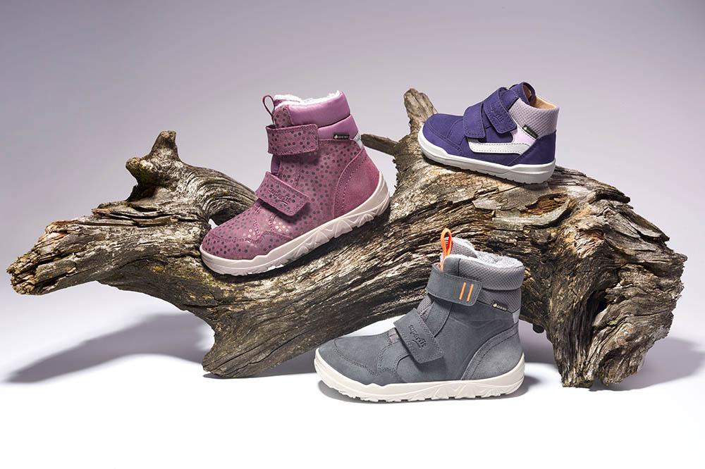 Three children's barefoot shoes from Superfit's Barefit collection displayed on driftwood